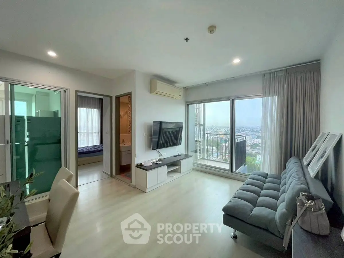 Modern living room with large windows offering stunning city views, sleek furniture, and stylish decor.