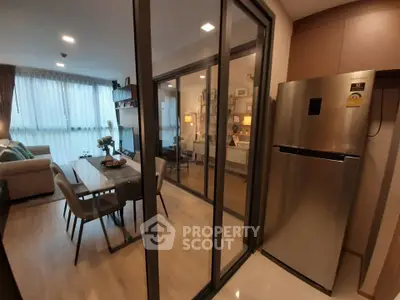 Modern apartment interior with open layout, featuring a stylish living room and dining area next to a sleek kitchen.
