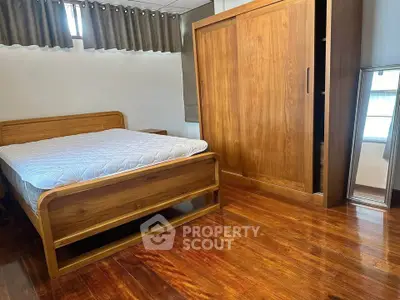 Spacious bedroom with wooden furniture and polished hardwood floors.
