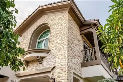 Charming two-story house with stone facade and lush greenery