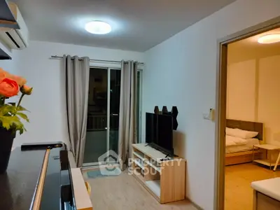 Modern living room with TV and access to cozy bedroom, featuring stylish decor and natural light.