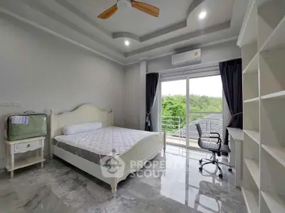 Spacious bedroom with balcony and modern furnishings, featuring a ceiling fan and natural light.