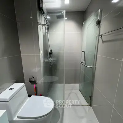 Modern bathroom with glass shower enclosure and sleek gray tiles