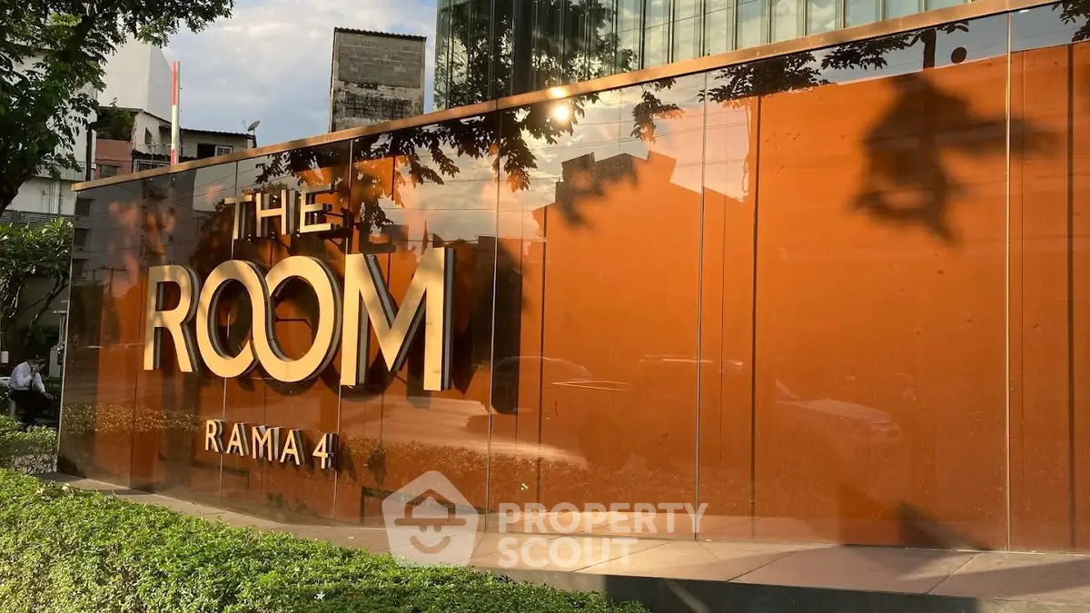 Modern building entrance with sleek glass facade and bold signage at The Room Rama 4.