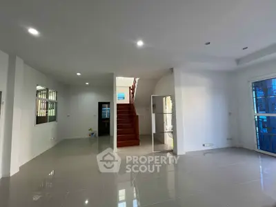 Spacious modern living room with glossy tile flooring and staircase
