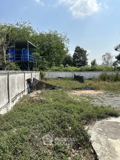 Spacious outdoor plot with lush greenery and water storage tanks, ideal for development opportunities.