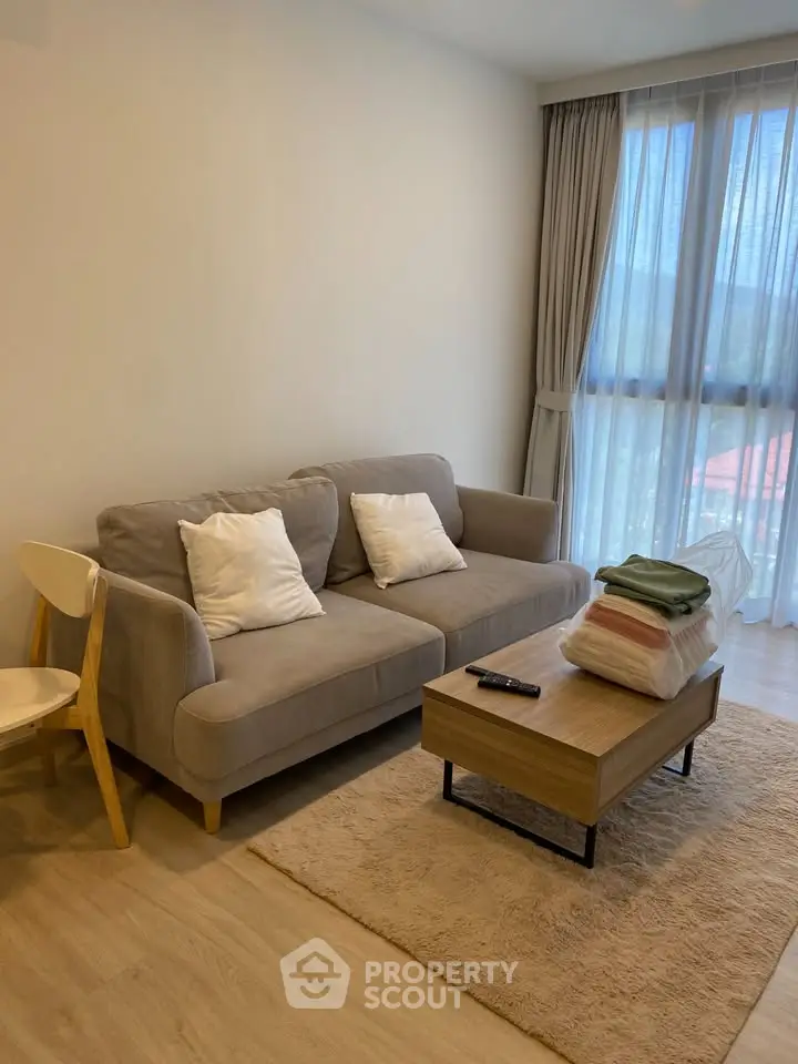 Cozy living room with modern sofa, wooden coffee table, and large window with curtains.