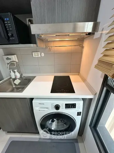 Modern kitchen with sleek appliances and compact design, featuring an induction cooktop and washing machine.