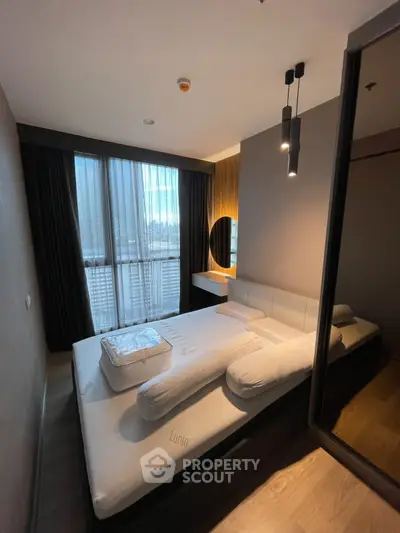 Modern bedroom with stylish lighting and large window, featuring a comfortable bed and elegant decor.