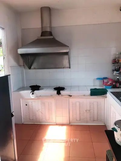 Spacious kitchen with dual gas stoves and modern range hood, perfect for culinary enthusiasts.