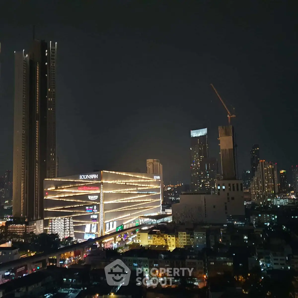 Stunning night view of city skyline with illuminated skyscrapers and construction crane.