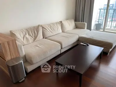 Spacious living room with modern beige sofa and sleek coffee table near balcony.