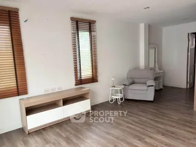 Spacious living room with modern decor and natural light, featuring wooden floors and stylish blinds.