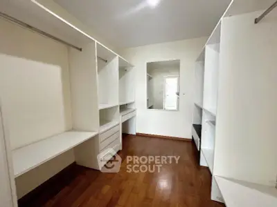 Spacious walk-in closet with wooden flooring and ample storage space.