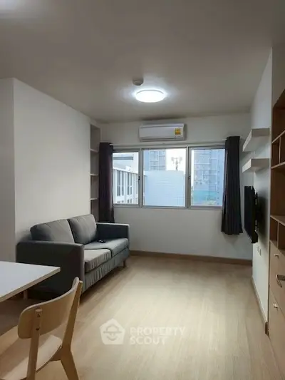 Modern living room with natural light and city view, featuring a cozy sofa and sleek wooden flooring.