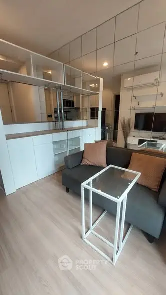 Modern living room with sleek furniture and mirrored wall for spacious feel.