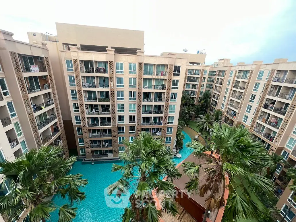 Stunning view of modern apartment complex with pool and lush palm trees.