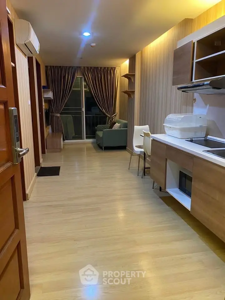 Modern open-layout living room with kitchen, featuring wooden flooring and stylish furniture.