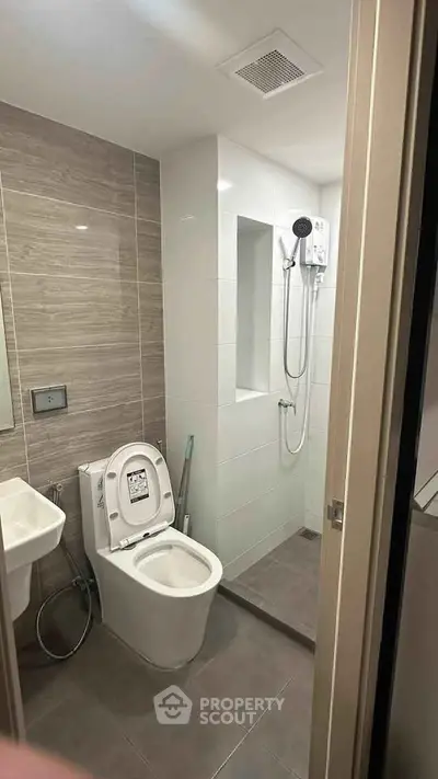 Modern bathroom with sleek design featuring a shower and toilet in a compact space.
