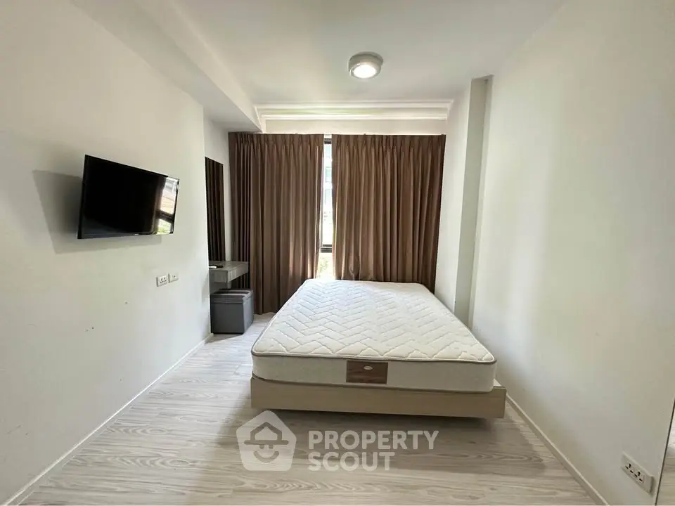 Modern bedroom with minimalist design, featuring a wall-mounted TV and large window with curtains.