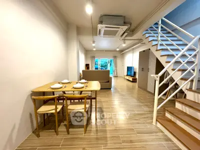 Spacious open-plan living and dining area with modern staircase and natural light.