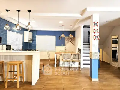 Spacious open-plan kitchen with modern lighting and wooden flooring, perfect for entertaining.