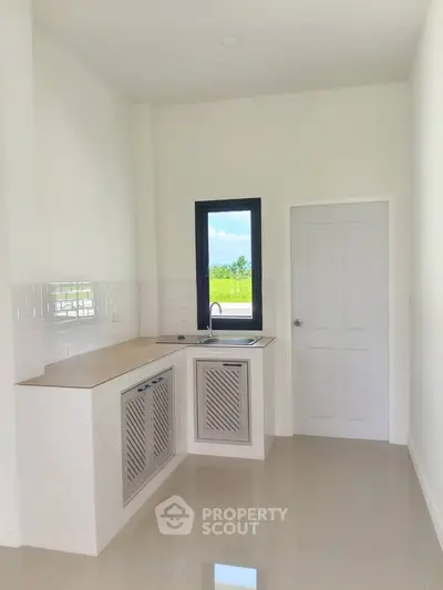 Bright modern kitchen with sleek white cabinetry and a scenic window view, perfect for culinary creativity.