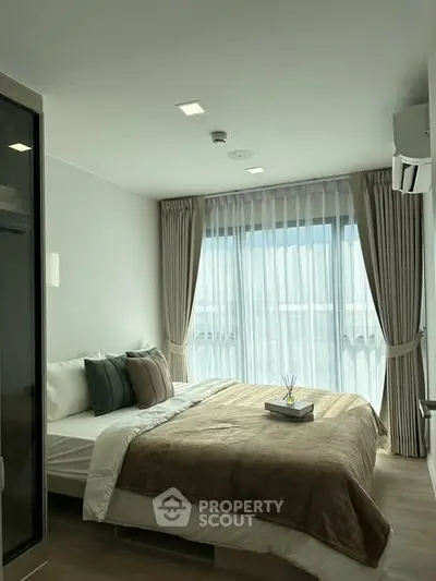 Modern bedroom with large window and elegant decor in a stylish apartment.