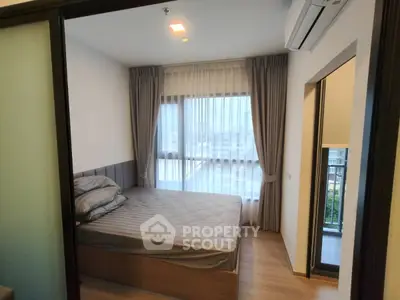 Cozy bedroom with large window and balcony access in modern apartment