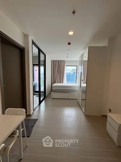 Modern studio apartment with sleek design and large windows offering city views.