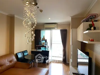 Stylish living room with modern chandelier and balcony view in a cozy apartment.