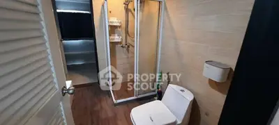 Modern bathroom with shower and toilet, featuring wood-style flooring and neutral tones.