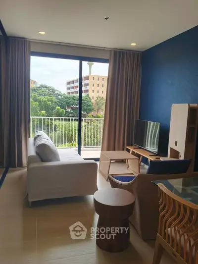 Modern living room with large windows and balcony view, featuring stylish furniture and natural light.