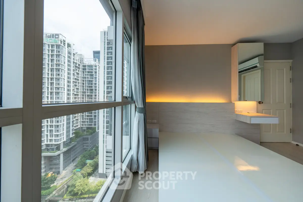 Modern bedroom with large windows offering stunning city views in a high-rise apartment.
