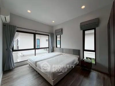 Modern bedroom with large windows and twin beds in a stylish apartment.
