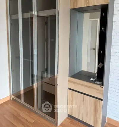 Modern bedroom with sleek glass wardrobe and wooden flooring