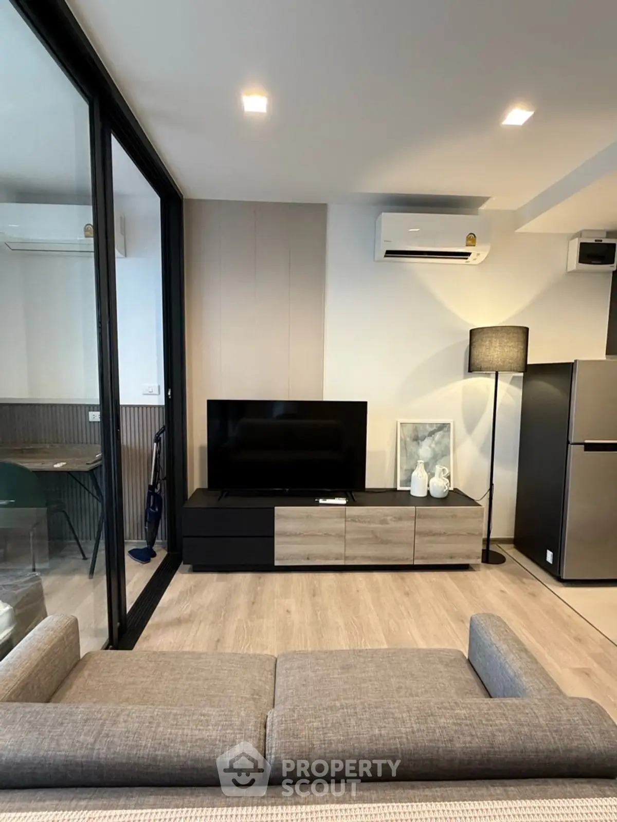 Modern living room with sleek furniture and large TV, featuring a stylish open layout.