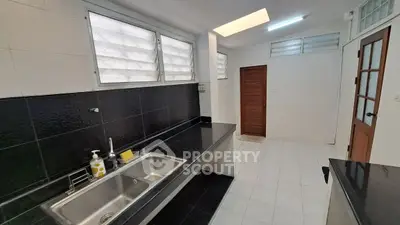 Spacious kitchen with sleek countertops and dual sink, featuring ample natural light and modern design.