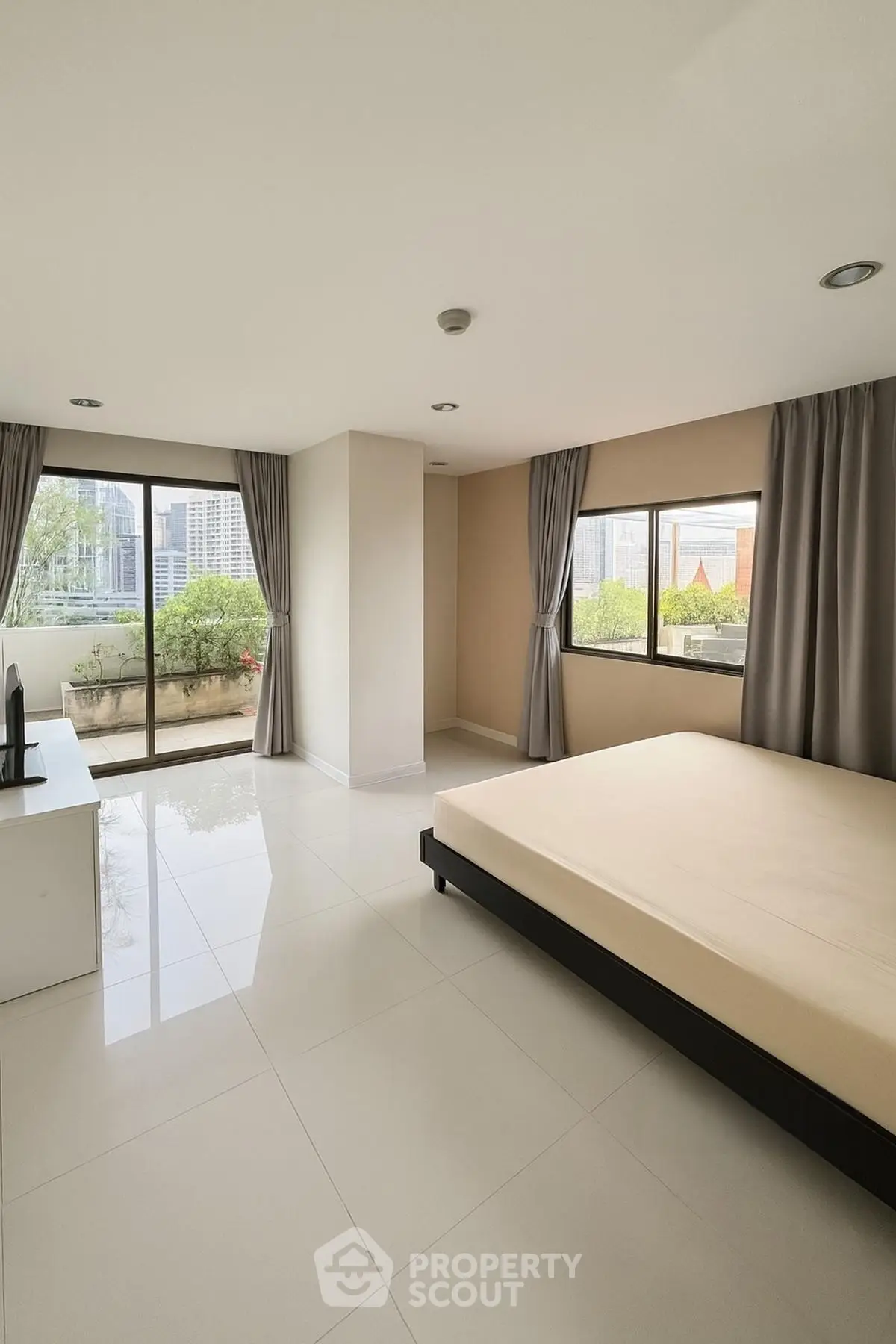 Spacious bedroom with large windows and balcony access in modern apartment