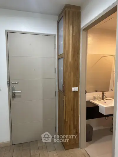 Modern apartment entrance with wooden flooring and compact bathroom view.