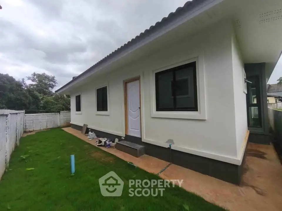 Modern single-story house with white exterior and lush green lawn, showcasing contemporary design and serene surroundings.
