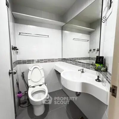 Modern bathroom with sleek fixtures and large mirror in a contemporary apartment.