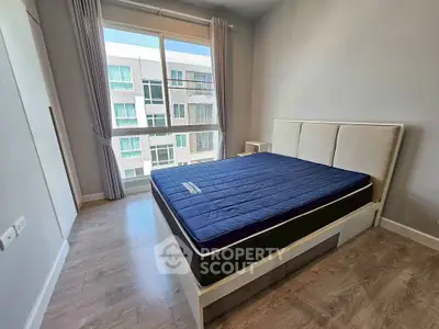 Modern bedroom with large window and stylish bed in a contemporary apartment.