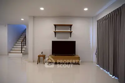 Modern living room with sleek TV setup and elegant staircase