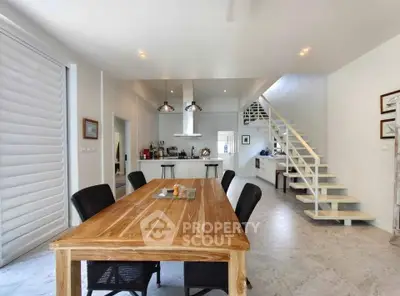 Spacious modern dining area with open kitchen and stylish staircase in a contemporary home.