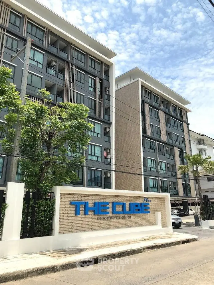 Modern condominium building with stylish facade and lush greenery, ideal urban living in prime location.