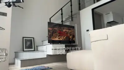 Modern living room with sleek staircase and mounted TV, showcasing contemporary design.