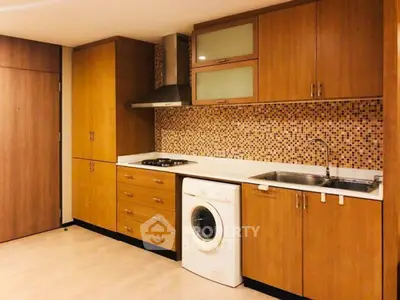 Modern kitchen with wooden cabinets, mosaic backsplash, and built-in washing machine.