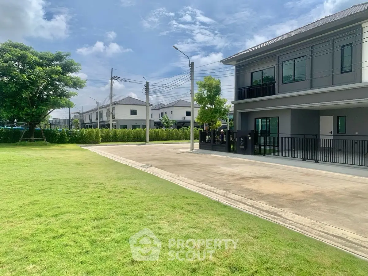 Modern suburban homes with spacious green lawn and clear blue sky.