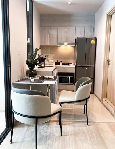 Modern compact kitchen with sleek appliances and cozy dining area in a stylish apartment.